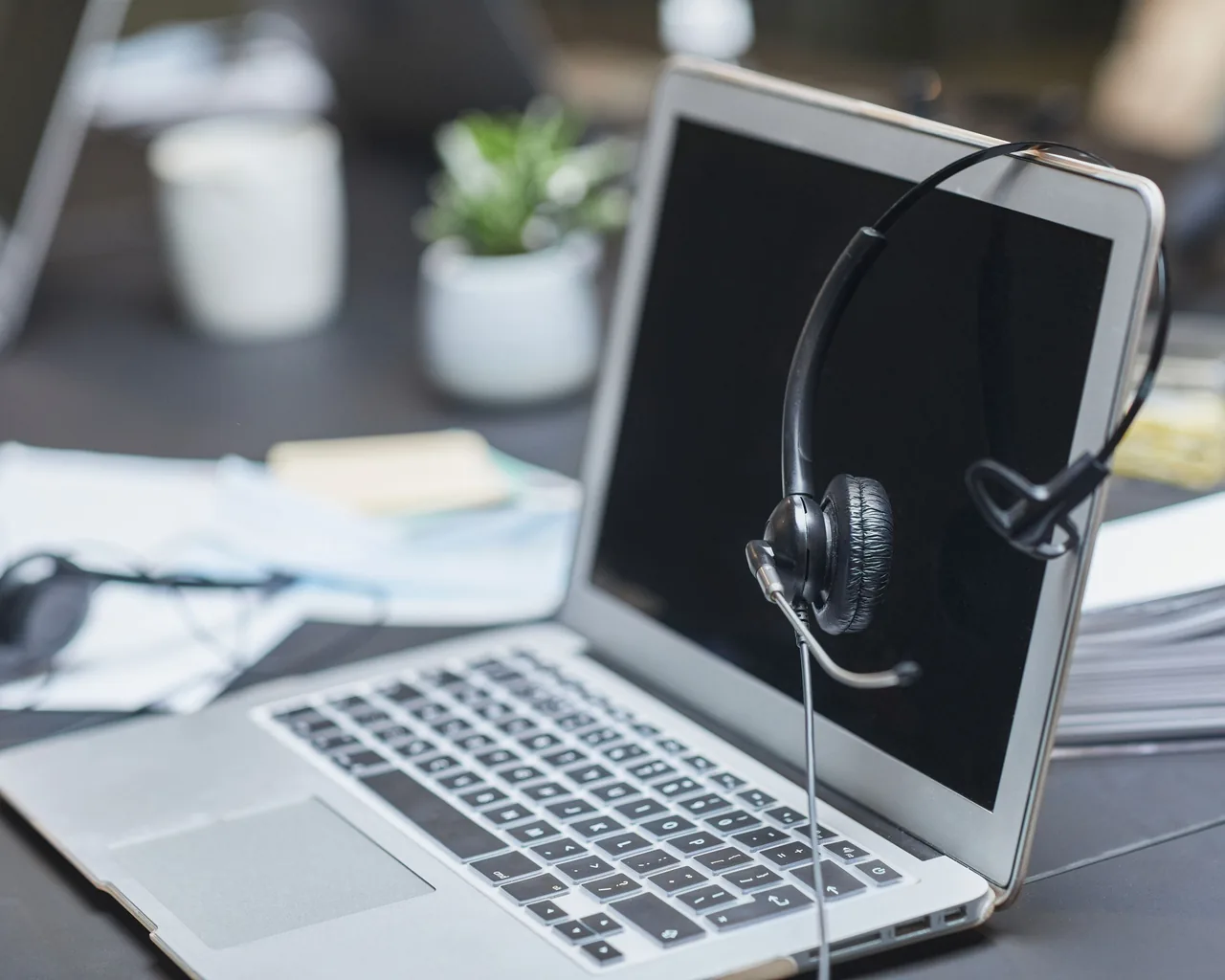 A support headset resting on a laptop at a help-desk table